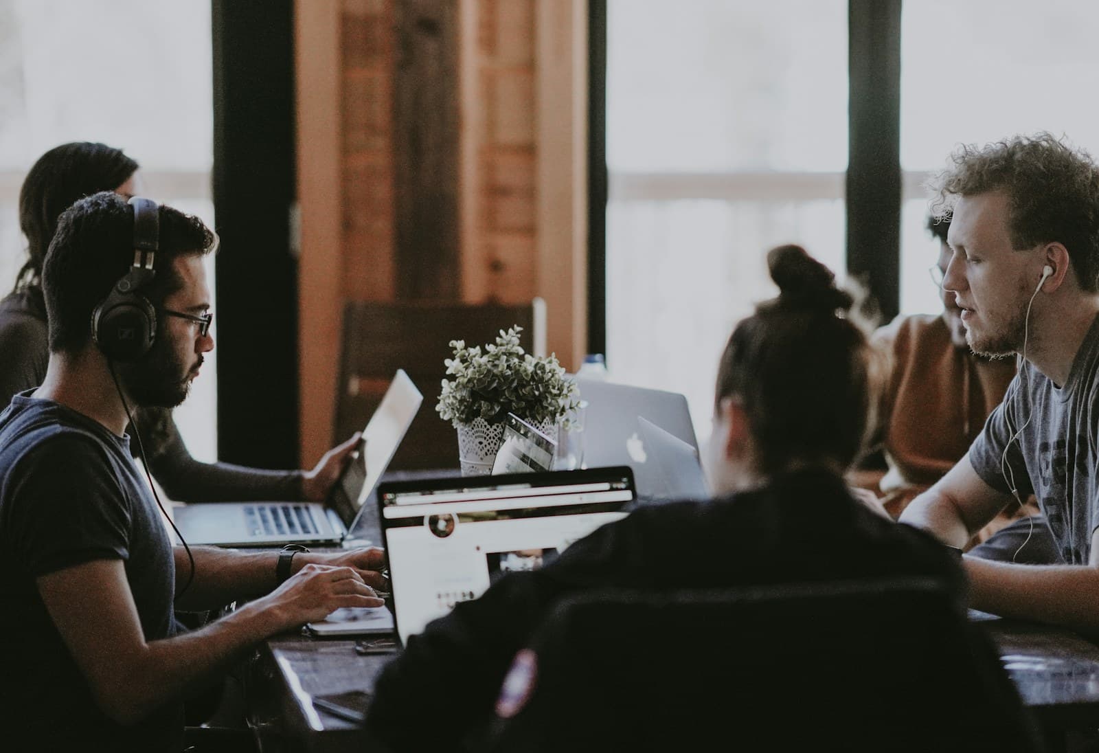 A small group sharing a workspace with laptops and notebooks
